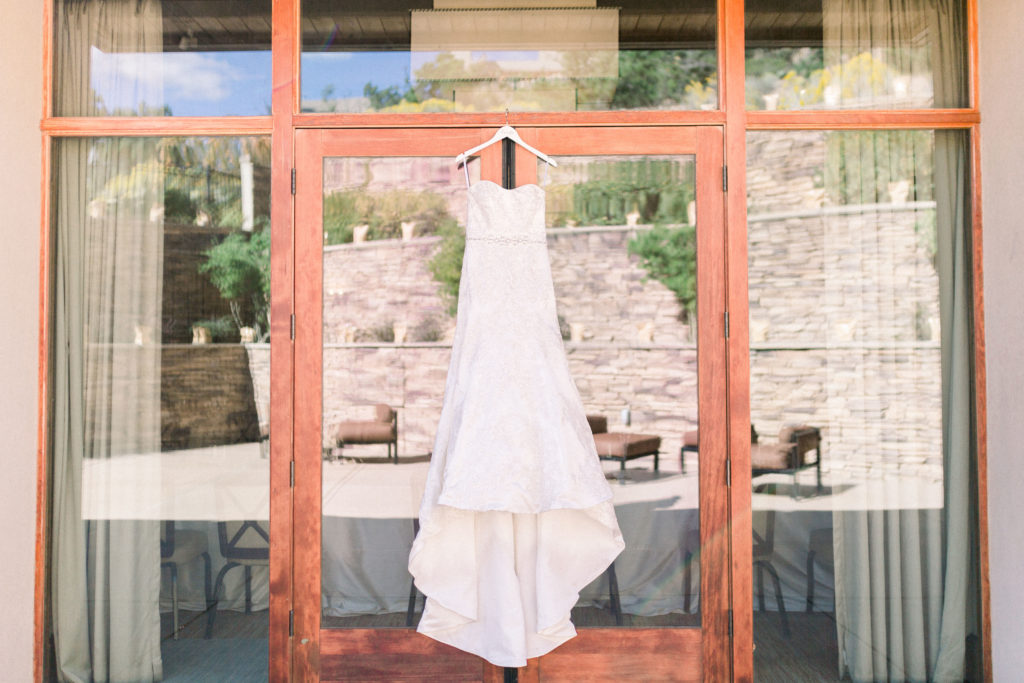 Gorgeous wedding gown in Santa Fe, New Mexico, shot at a local wedding venue - Four Seasons at Rancho Encantado. The wedding gown hangs against glass doors, reflecting the outdoor wedding space.