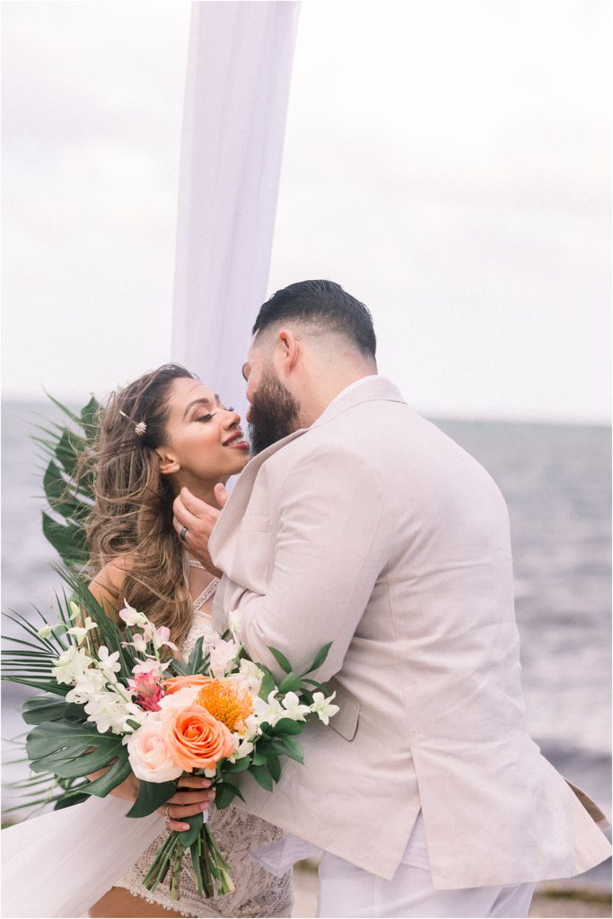 Close up of the gorgeous couple after saying their vows during their beach elopement, Dr. Beau Hightower kisses Lais DeLeon in his tan suit, and she is wearing a custom couture wedding gown. Shot by the best Albuquerque based adventure wedding photographer Shayla Cristine Photography.