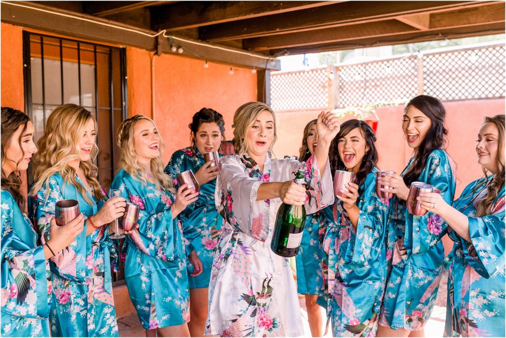 Bridal party fun - the bride is popping a bottle of champagne for her bridesmaids at the ABQ Biopark in Albuquerque on her wedding day. Shot by New Mexico wedding photography team Shayla Cristine Photography.